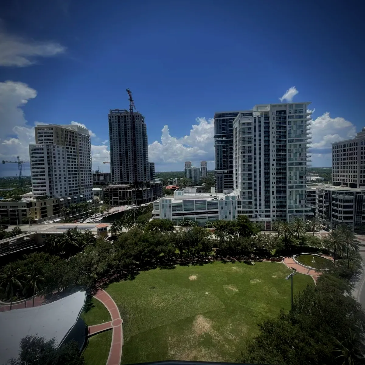 A downtown Florida skyline above a riverside park, in graded afternoon light.